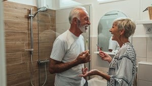 Smiling older couple standing in their bathroom