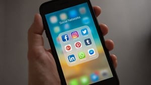 A phone in someone's hand, open on social media apps.