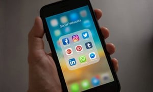 A phone in someone's hand, open on social media apps.