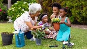 A grandmother with her daughter and two young granddaughters gardening together