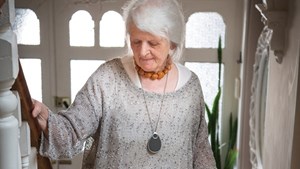Person wearing personal alarm pendant walking up the stairs at home