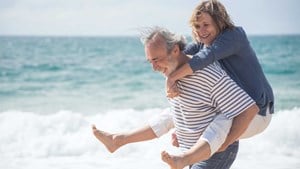 Man-giving-a-woman-a-piggy-back-on-the-beach_16.9